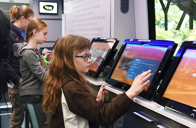 Catherine Markway, 8, and her sister, Anna, visit the touch screens on the C-SPAN bus during its visit to Jefferson City on Tuesday as part of its 50-state capitals tour. The sisters were on board with their mom, Jennifer, and brother, Benjamin, 9. The bus was parked briefly at the Capitol where a number of residents toured the customized tour bus filled with electronic communications; it also visited Lewis and Clark and Thomas Jefferson middle schools.