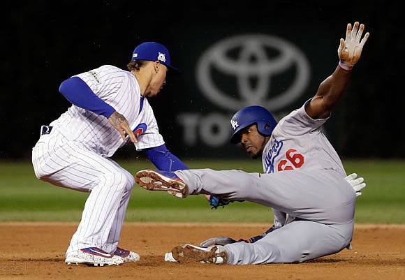 Javier Baez of the Cubs tags out Yasiel Puig of the Dodgers at second base during the ninth inning of Tuesday night's game in Chicago.