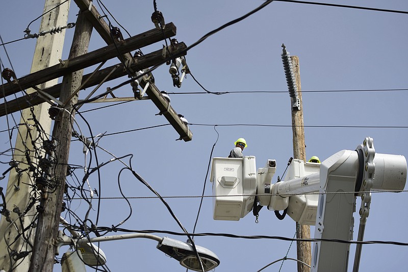 In this Thursday, Oct. 19, 2017 photo, a brigade from the Electric Power Authority repairs distribution lines damaged by Hurricane Maria in the Cantera community of San Juan, Puerto Rico. The storm struck after the Authority had filed for bankruptcy in July, put off maintenance and had finished dealing with outages from Hurricane Irma. (AP Photo/Carlos Giusti)