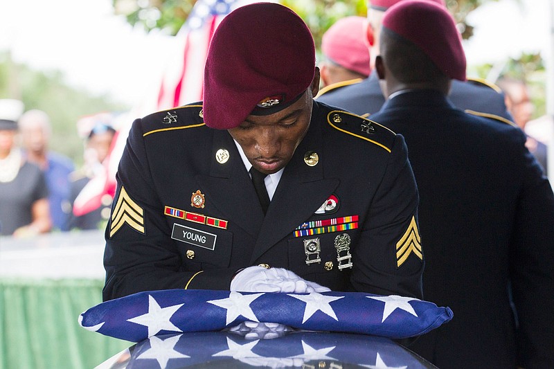 Sgt. Donald Young places a U.S. flag over the casket of Sgt. La David Johnson during his burial service at Fred Hunter's Hollywood Memorial Gardens in Hollywood, Fla., on Saturday, Oct. 21, 2017. Mourners remembered not only a U.S. soldier whose combat death in Africa led to a political fight between President Donald Trump and a Florida congresswoman but his three comrades who died with him. (Matias J. Ocner/Miami Herald via AP)