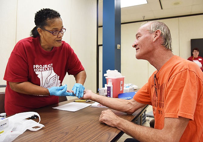 2017 FILE: Joyce Hill talks to David Crowe as she prepares to stick his finger for a blood sugar test. Hill is an LPN and attends Second Baptist Church; she was one of numerous people helping at the Project Homeless Connect event. 