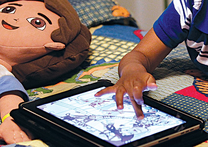 In this Friday, Oct. 21, 2011, file photo, a child plays with an iPad in his bedroom. Parents of small children have long been hearing about the perils of "screen time." And with more screens, it's only getting worse. But working, taking care of children and remembering to eat is exhausting. Parents need those minutes of quiet. So maybe it's time to relax a little. 