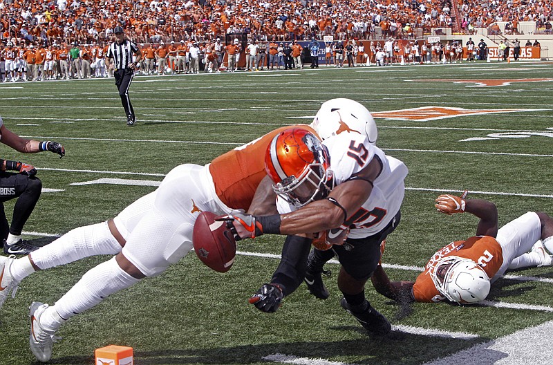 Oklahoma State receiver Chris Lacy (15) fumbles the ball while reaching for the goal line as Texas' DeShon Elliott defends during the second half of an NCAA college football game Saturday against Texas in Austin. The ball went out of bounds and was retained by Oklahoma State. Oklahoma State won, 13-10, in overtime.