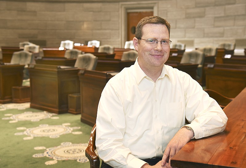 Patrick Baker poses in the Missouri Senate chambers where he serves as Senate Administrator.