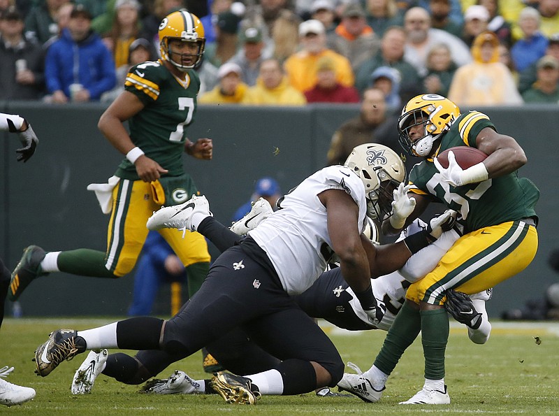 Green Bay Packers running back Aaron Jones (33) is tackled by New Orleans Saints defensive tackle David Onyemata (93) and strong safety Kenny Vaccaro (32) during the first half of an NFL football game Sunday in Green Bay, Wis.