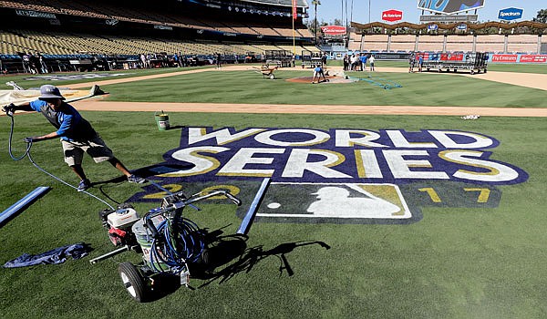 Oscar Del Real paints the World Series logo on the field Monday at Dodgers Stadium before media day for the World Series between the Astros and the Dodgers in Los Angeles.