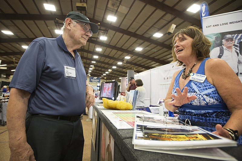 Jack Octgen of Livingston, Texas, visits with Janet Trannum, certified health coach, at the Take Shape For Life booth Wednesday at the 44th annual rally hosted by Family Motor Coach. This year's event brought more than 300 RVs to the Four States Fairgrounds for the four-day event.