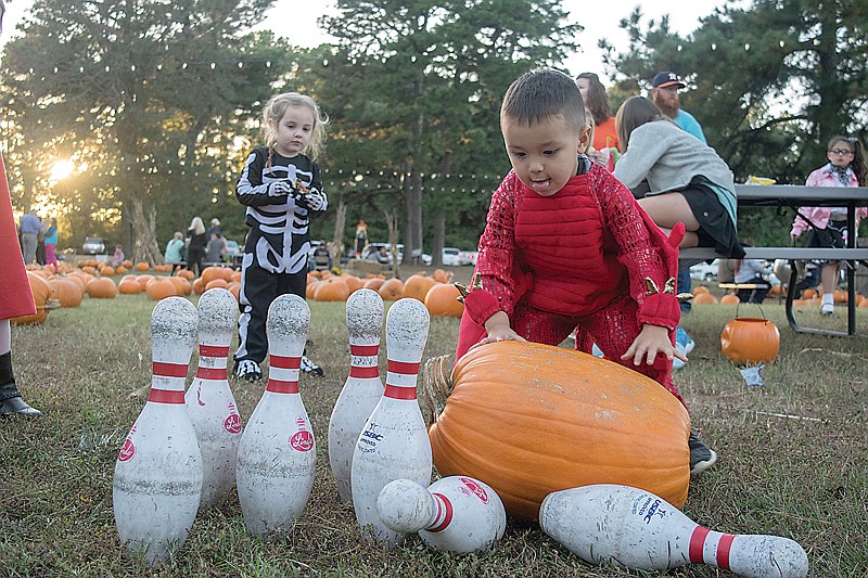 Two-year-old Nolan Ames rolls a giant pumpkin through bowling pins Wednesday evening at the Williams Memorial United Methodist Church's Pumpkin Palooza.