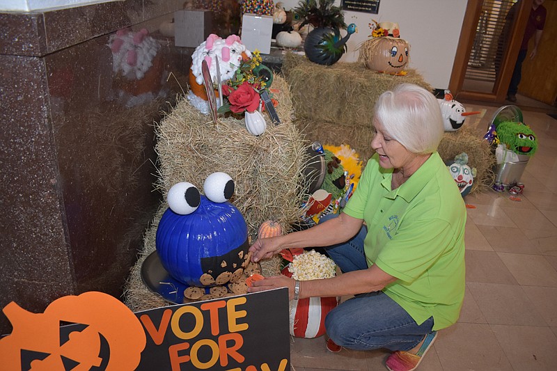 Nancy Herron checks the level of chocolate chip cookies on her decorated pumpkin Wednesday in the lobby at Miller County Courthouse in Texarkana, Ark. The pumpkins were decorated to celebrate art skills and Halloween.