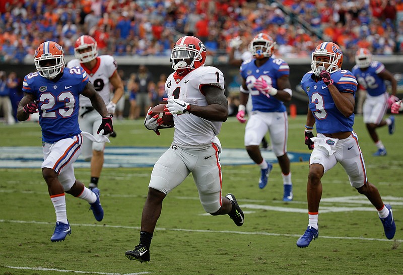 Georgia running back Sony Michel (1) runs past the Florida defense including defensive back Chauncey Gardner Jr. (23), and cornerback Marco Wilson (3) for a touchdown run in the first half of an NCAA college football game, Saturday, Oct. 28, 2017, in Jacksonville, Fla. 