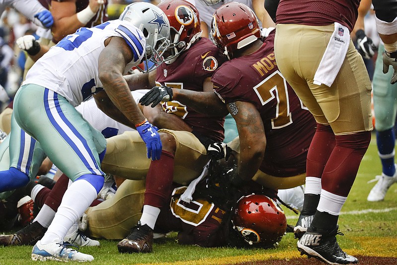 Washington Redskins running back Rob Kelley (20) (bottom) plows through the line to score a touchdown during the first half of an NFL football game against the Dallas Cowboys in Landover, Md., Sunday, Oct. 29, 2017. 