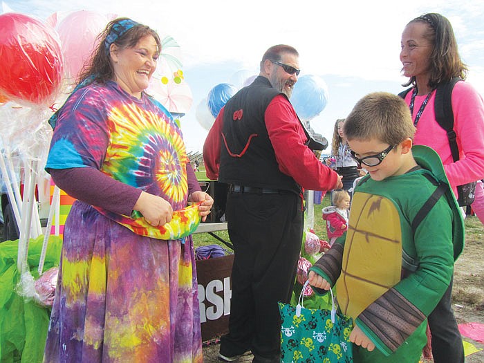 From left, Tracey Searcy and Charlie Hogshooter from Gerbes West hand out candy to Aiden Kirsch, 6, and mom, Mary, at the annual Jefferson City Jaycees Trunk-or-Treat event on Sunday at the fairgrounds. 