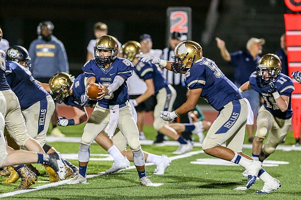 Helias quarterback Daniel Rhea holds the ball as Michael Stroesser prepares for a handoff during a game this season at Ray Hentges Stadium. Rhea and the Helias offense figure to get a stiff test tonight from the Moberly Spartans in the district title game at Moberly.