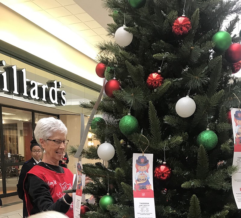 Mary Nell Short, a volunteer with The Salvation Army Women's Auxiliary, hangs angel tags on the tree at Central Mall. The Salvation Army, with the help of the community, is providing gifts to approximately 1,000 children and seniors this Christmas season.