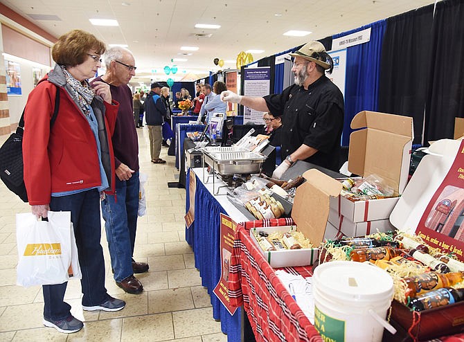 Wurstmeister Mike Sloan, of Hermann Wurst Haus, right, hands out sausage samples Friday to Nada and Bob Hunt, of Callaway County, during the Jefferson City Area Chamber of Commerce's annual small business expo at Capital Mall.