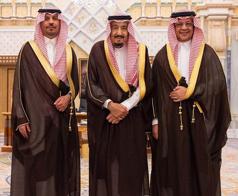 In this photo provided by the Saudi Press Agency, the new Economy and Planning Minister, Mohammad al-Tuwaijri, right and the new National Guard chief, Prince Khalid bin Ayyaf al-Muqrin, left, pose for a photo with King Salman during a swearing in ceremony, in Riyadh, Saudi Arabia, Monday, Nov. 6, 2017. The king has sworn in new officials to take over from a powerful prince and former minister believed to be detained in a large-scale sweep that has shocked the country and upended longstanding traditions within the ruling family. (Saudi Press Agency, via AP)