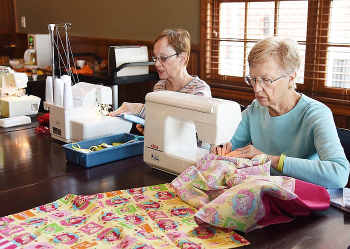 ABOVE: Connie May, at right, is seated at a sewing machine, while Ginger Beasley uses a surger machine. Both are making pillowcases for Ryan's Case for Smiles on Friday at Canterbury Winery in Holts Summit. 