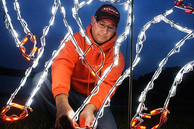 Volunteer Jeff Buker straightens lights on a reindeer Tuesday as he sets up for the Capital City Festival of Lights at Binder Lake Park. The festival begins Dec. 2 and some proceeds will go to various charities.