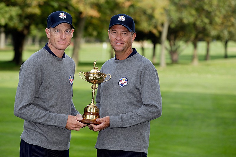 In this Sept. 25, 2012, file photo, USA's Ryder Cup captain Davis Love III, left, and player Jim Furyk pose with the Ryder Cup trophy during the Ryder Cup golf tournament, at the Medinah Country Club in Medinah, Ill. The Americans have a system where the same players are serving as captains or assistants at the Ryder Cup. 