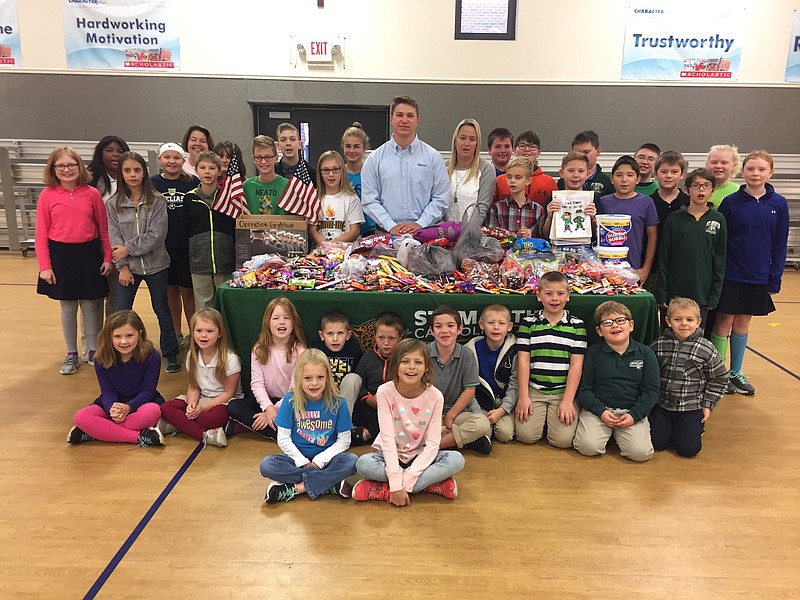 <p>Submitted by Angie Plunkett</p><p>Lane Plunkett, a junior at Helias High School, stands at center, with St. Martin Catholic School fifth-grade teacher Dawn Crader and the second-grade class at St. Martin. They are surrounded by a table of candy students donated for care packages for soldiers.</p>