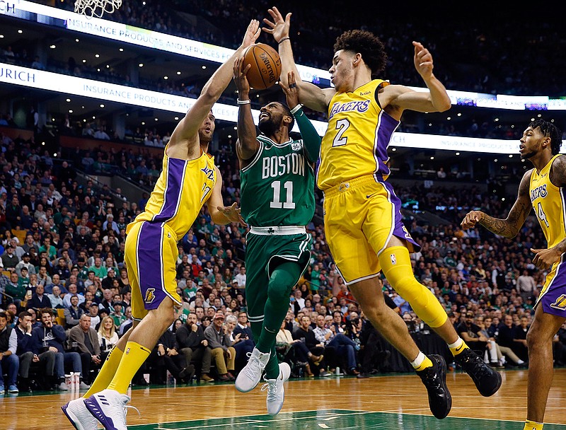 Boston Celtics guard Kyrie Irving (11) goes between Los Angeles Lakers' Lonzo Ball (2) and Brook Lopez during the fourth quarter of Boston's 107-96 win in an NBA basketball game in Boston on Wednesday, Nov. 8, 2017. 