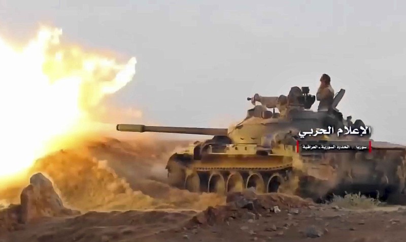 This frame grab from video provided Wednesday, Nov 8, 2017, by the government-controlled Syrian Central Military Media, shows a tank firing on militants' positions on the Iraq-Syria border. The United States and Russia are nearing an agreement on Syria for how they hope to resolve the Arab country’s civil war once the Islamic State group is defeated, officials said Nov. 9. (Syrian Central Military Media, via AP)