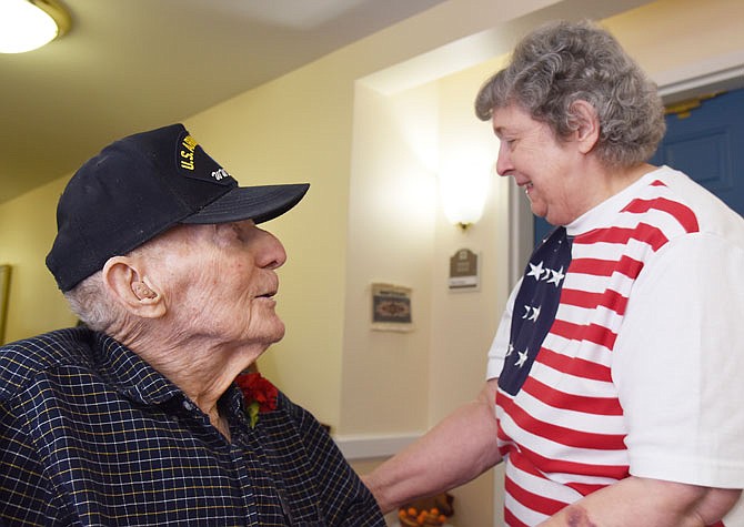 Vera Backman visits with Gregory Wankum, a World War II veteran, after pinning a red corsage on his lapel Friday at Heisinger Bluffs' Veterans Day event. 