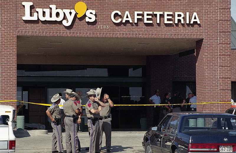  In this Oct. 16, 1991, file photo, police officers gather outside Luby's Cafeteria in Killeen, Texas, at the scene where a gunman killed 23 people including himself, with semi-automatic gunfire during lunchtime.