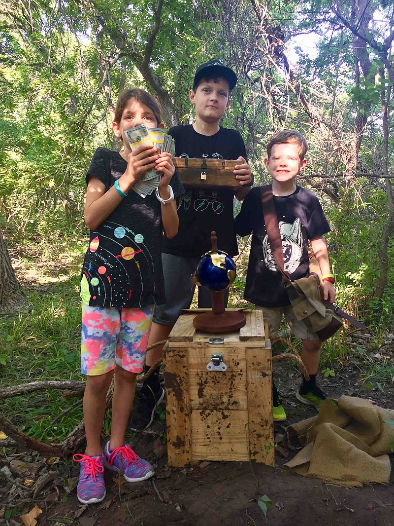 Katherine Ayers, 9, and her brothers Christopher, 11, and Daniel, 8, pose with their reward for winning this summer's Brain Chase competition—$10,000 and a Magellan globe. Their family traveled to the Texas panhandle to dig up the treasure chest they located by solving a difficult series of riddles and clues in the online contest. (Submitted photo)
