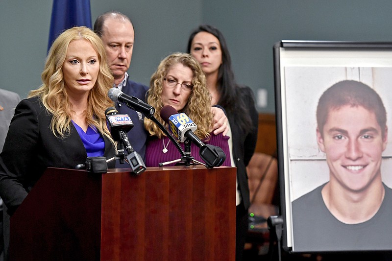 FILE – In this May 5, 2017, file photo, Centre County, Pa., District Attorney Stacy Parks Miller, left, announces findings an investigation into the death of Penn State University fraternity pledge Tim Piazza, seen in photo at right, as his parents, Jim and Evelyn Piazza, second and third from left, stand nearby during a news conference in Bellefonte, Pa. Parks Miller announced Monday, Nov. 13, 2017, that more charges have been filed against fraternity brothers after investigators recovered deleted surveillance video footage recorded before the Feb. 4, 2017, death of Piazza, of Lebanon, N.J., after a night of heavy drinking. (Abby Drey/Centre Daily Times via AP, File)/Centre Daily Times via AP)