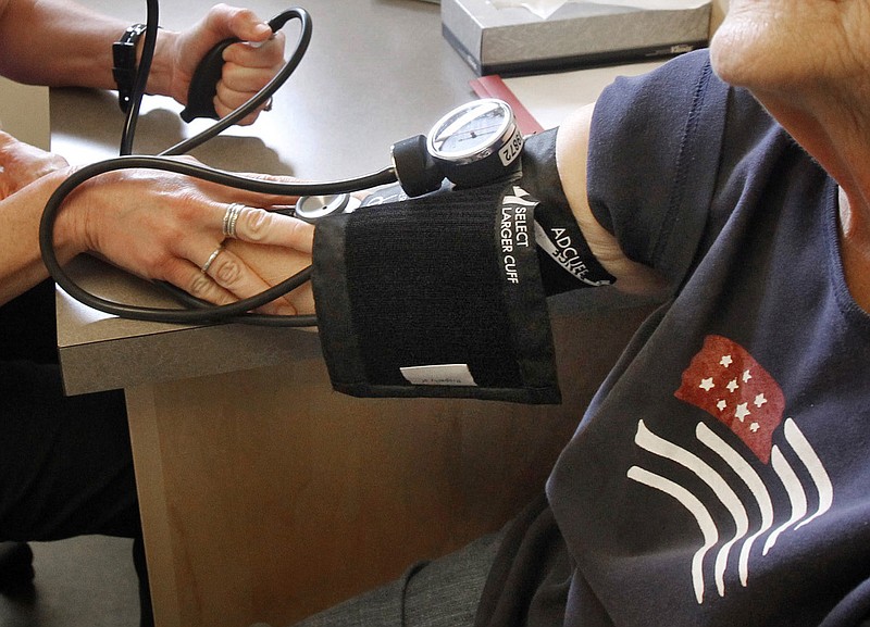 A patient has her blood pressure checked by a registered nurse.