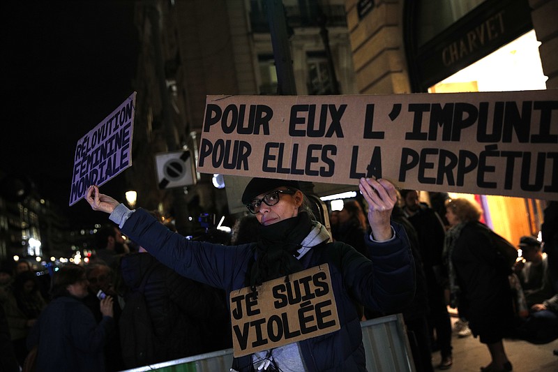 A activist holds a banner reading: "For him impunity, for her a life sentence" during a protest in Paris, Tuesday, Nov. 14, 2017. Justice Minister Nicole Belloubet provoked consternation and dismay among feminist groups by saying a legal minimum age of 13 for sexual consent "is worth considering." (AP Photo/Christophe Ena)