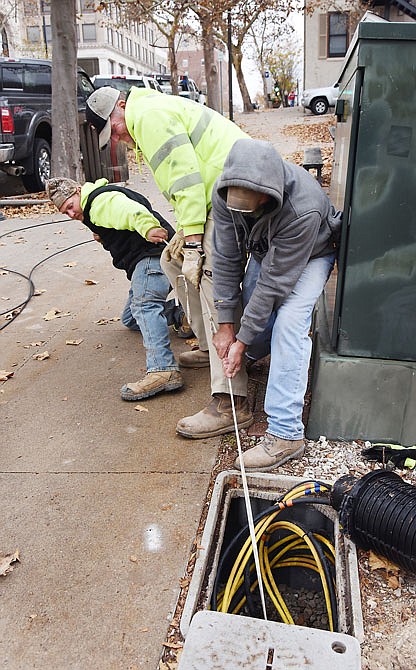 From left, David Bentlage, Mark Roettgen and Nathan Hale try to pull fiber optic cable through an underground pipe Tuesday morning. All are employees of Ridenhour Directional Drilling and were installing cable for Socket internet service under the 300 block of Madison Street.
