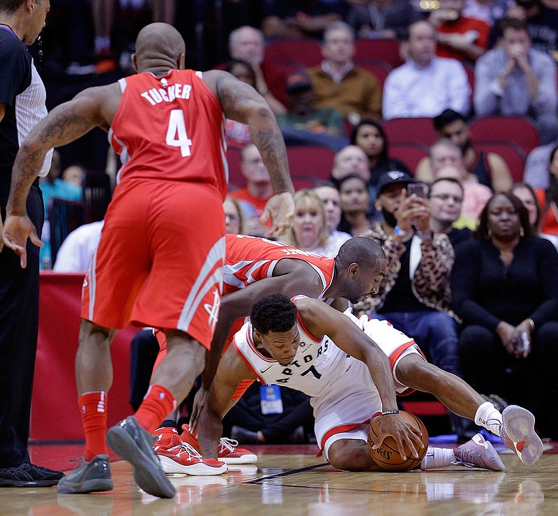 Houston Rockets forward Luc Mbah a Moute (12) and Toronto Raptors guard Kyle Lowry (7) battle for a loose ball as forward PJ Tucker (4) moves in during the first half of an NBA basketball game, Tuesday, Nov. 14, 2017, in Houston. 