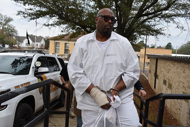 Stacey Eugene Johnson is escorted by law enforcement officers Wednesday morning near the south side entrance to the Sevier County Courthouse in De Queen, Ark. He was in court to plea for additional DNA testing to prove he is innocent in a 1993 murder.