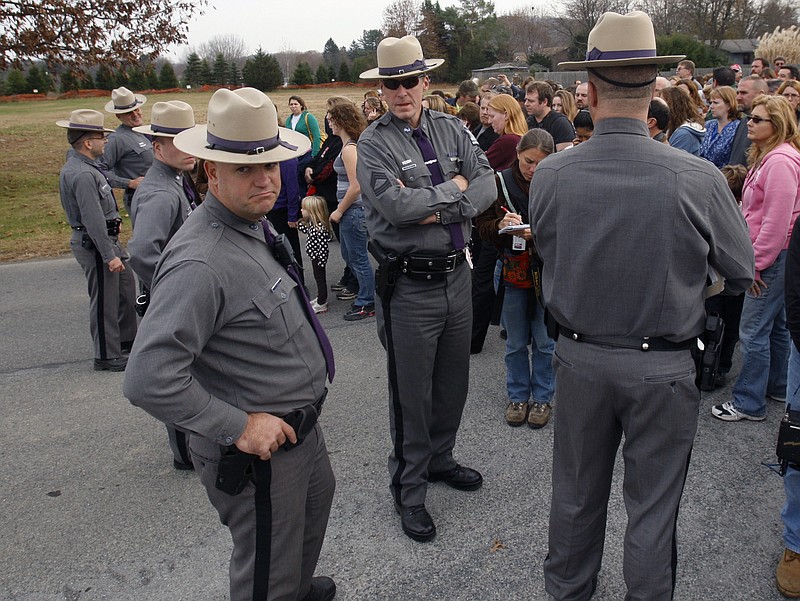 FILE--This photo from Tuesday, Nov. 10, 2009 shows New York State Police waiting with families for students to be released after a lockdown at Stissing Mountain Middle School and High School in Pine Plains, N.Y.  The president of the National Association of School Resource Officers says schools regularly practice safety plans and have gotten good at taking action anytime they hear about a potential threat in or outside the building.   (AP Photo/Mike Groll, File)