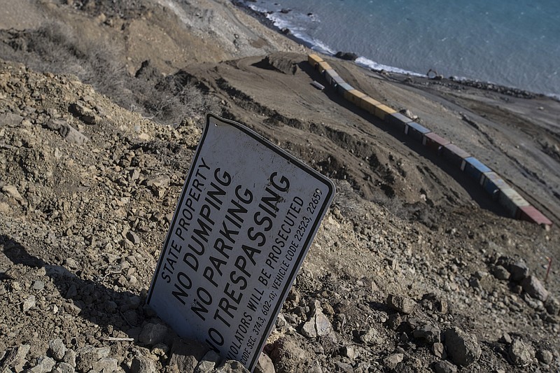 A highway sign was placed uphill on a ridge along the Mud Creek slide to help workers locate a roped path toward the top of the slide as they reconstruct Highway 1 in southern Monterey County, Calif., on Sept. 20, 2017. 