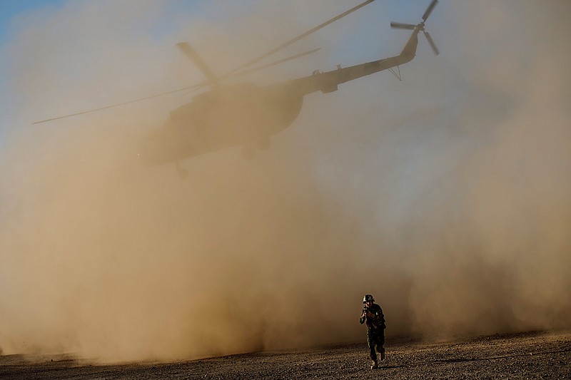 A soldier with the Afghan army leaves the landing site as an Afghan Mi-17 takes off during training near Camp Shorab, in Helmand Province. 
