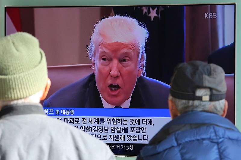 People watch a TV screen showing an image of U.S. President Donald Trump at the Seoul Railway Station in Seoul, South Korea, Tuesday, Nov. 21, 2017. Trump announced Monday the U.S. is putting North Korea's "murderous regime" on America's terrorism blacklist, despite questions about Pyongyang's support for international attacks beyond the assassination of its leader's half brother in February. The signs read "Threat to the world." 