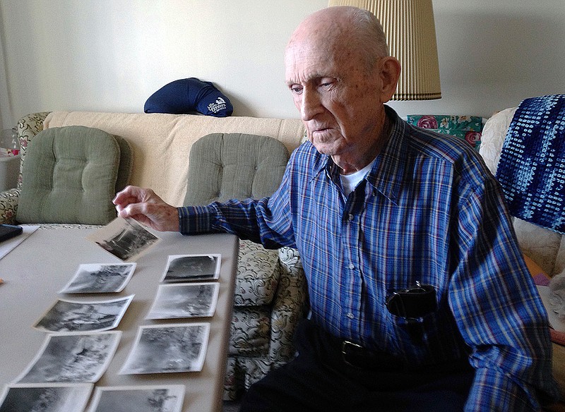 In this Tuesday, Nov. 21, 2017, photo, World War II veteran Kenneth F. Lincoln, 90, looks at photos in his North Attleborough, Mass., home that were taken when he was serving in the U.S. Navy and fighting a large fire that broke out among straw huts in Rabat, Morocco in the summer of 1946 . Lincoln is finally getting the military decoration he earned for fighting the blaze, and will receive a Moroccan award for meritorious conduct on Sunday, Nov. 26 in North Attleborough. 
