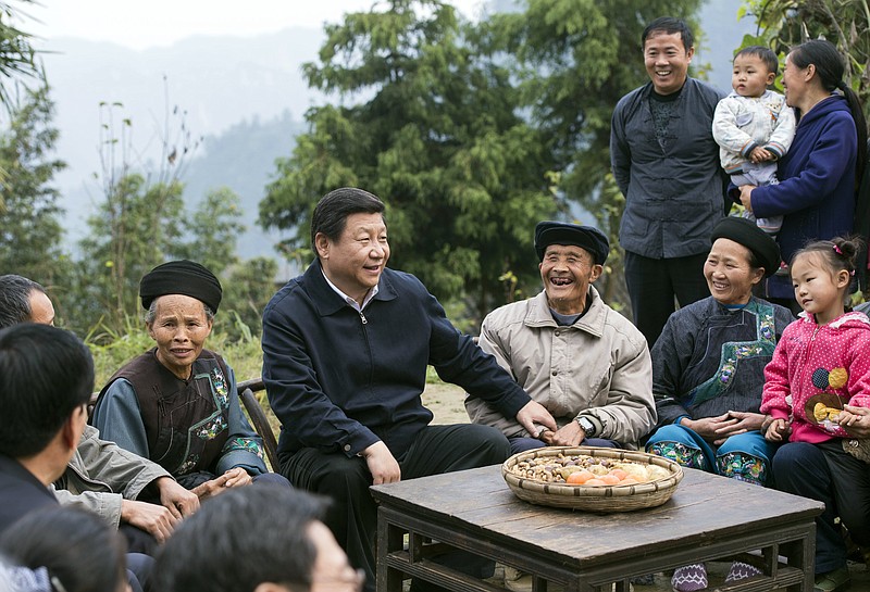 In this Nov. 3, 2013, photo released by Xinhua News Agency, Chinese President Xi Jinping, center, talks with local villagers and cadres at Shibadong village in Paibi Township of Huayuan County in the Tujia-Miao Autonomous Prefecture of Xiangxi in central China's Hunan Province. At the start of his second five-year term as leader of China's ruling Communist Party, Xi is at the center of China's most colorful efforts to build a cult of personality since the death of the founder of the People's Republic, Mao Zedong, in 1976.