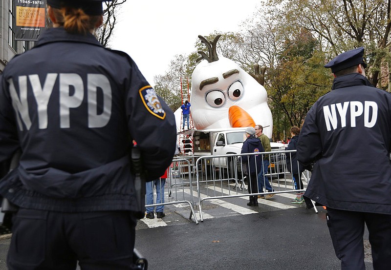 Police officers stand near the site where a large balloon of Olaf, from the animated film, "Frozen", is being inflated for the Thanksgiving Day parade in New York, Wednesday, Nov. 22, 2017. Sand-filled sanitation trucks and police sharpshooters will mix with glittering floats and giant balloons at a Macy's Thanksgiving Day Parade that comes in a year of terrible mass shootings and a deadly truck attack in lower Manhattan. (AP Photo/Seth Wenig)