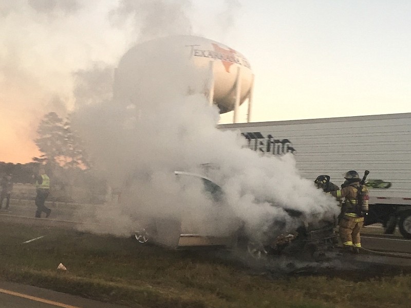 Smoke billows from an SUV as Texarkana, Texas, firefighters extinguish the flames Thursday in the westbound lane of Interstate 30 near the Texarkana Travel Information Center. No one was injured in the blaze, which happened about 5:15 p.m. ( Photo courtesy Justin Turner)