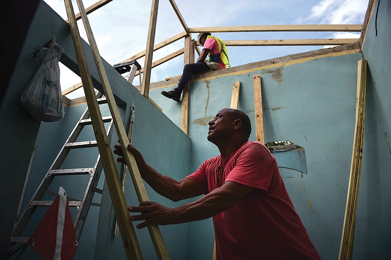 Pedro Deschamps helps workers hired by FEMA to carry out the installation of a temporary awning roof at his house, which suffered damage during Hurricane Maria, in San Juan, Puerto Rico, Wednesday, Nov. 15, 2017. A newly created Florida company with an unproven record won more than $30 million in contracts from the Federal Emergency Management Agency to provide emergency tarps and plastic sheeting for repairs to hurricane victims in Puerto Rico. Bronze Star LLC never delivered those urgently needed supplies, which even months later remain in demand on the island. 