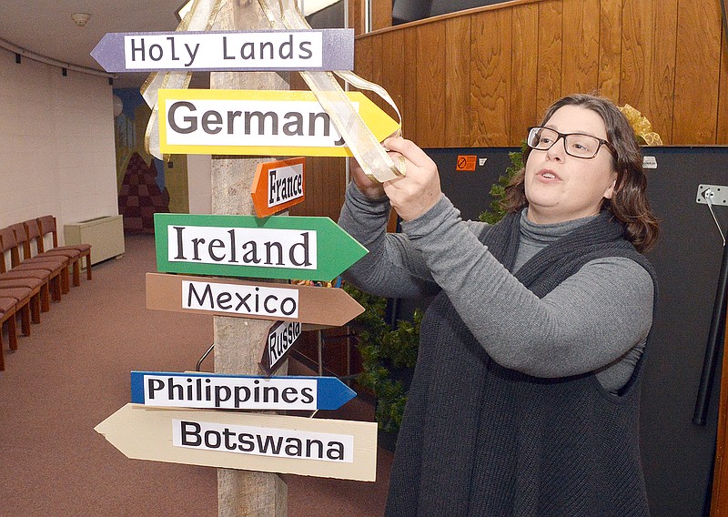 The Rev. Bethany Imbler Albrecht, of Community Christian Church, prepares a directional signpost Tuesday for the upcoming  annual Christmas Around the World event, which explores the different Christmas celebrations of nine countries around the world.