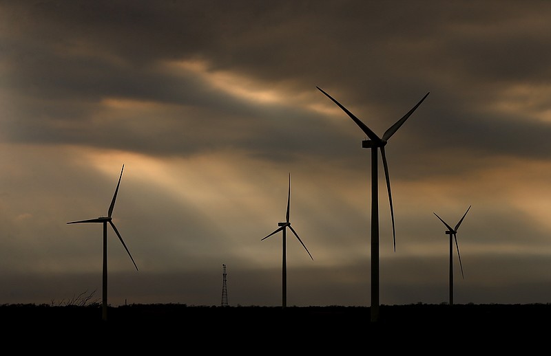 In this Tuesday, Nov. 28, 2017, photo, Rays of sunlight try to break through darkening clouds over a wind farm near Waverly, Kan. 