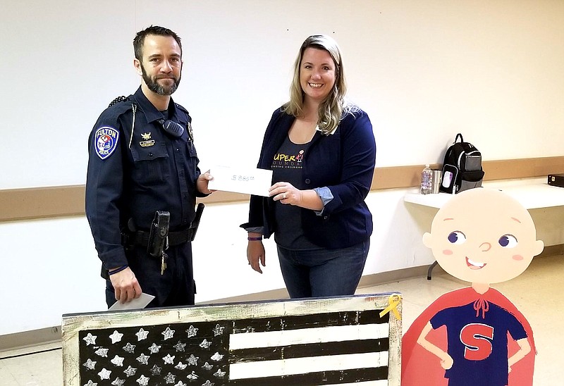 On Nov. 30, 2017, officer Adam Cramer, left, of the Fulton Police Department presented a donation to Super Sam Foundation cofounder Cassie Santhuff. Super Sam raises money and awareness to fight childhood cancer.