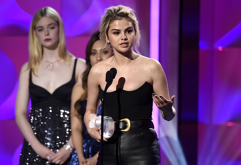 Selena Gomez accepts the woman of the year award at the Billboard Women in Music event at the Ray Dolby Ballroom on Thursday, Nov. 30, 2017, in Los Angeles. Looking on from left are presents Elle Fanning and Francia Raisa. (Photo by Chris Pizzello/Invision/AP)