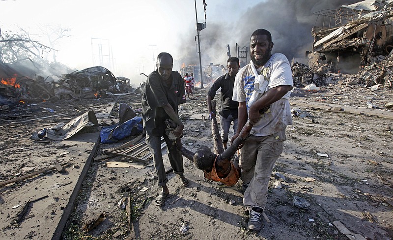 FILE - In this Saturday, Oct. 14, 2017 file photo, Somalis remove the body of a man killed in a blast in the capital Mogadishu, Somalia. The final death toll from the Oct. 14 massive truck bombing in Somalia's capital is 512 people, according to a report by the committee tasked with looking into the country's worst-ever attack, obtained by The Associated Press Saturday, Dec. 2, 2017. (AP Photo/Farah Abdi Warsameh, File)