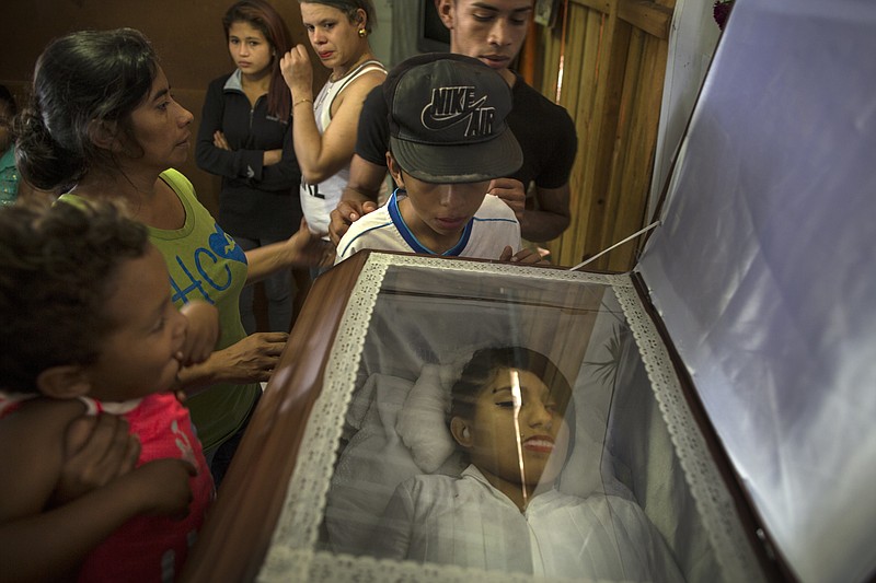 Family and friends gather around the coffin containing the remains of his sister Kimberly Dayana Fonseca, 19, in Tegucigalpa, Honduras, Saturday, Dec. 2, 2017. As the electoral count entered its sixth day Saturday, Fonseca was shot to death at a protest supporting opposition presidential candidate Salvador Nasralla by gunmen in two vehicles who witnesses say were police.  (AP Photo/Rodrigo Abd)